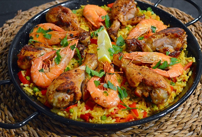 Spaanse Paella met grote garnalen en drumsticks in een paella pan