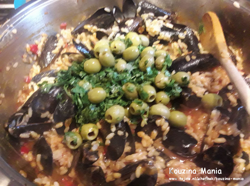 Mosselen met risotto in een pan met olijven peterselie en koriander
