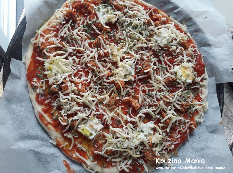 Pizza tonijn en mozzarella bestrooien met basilicum